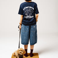 Person wearing a black t-shirt with text and graphics, standing with a dog on a leash against a white background